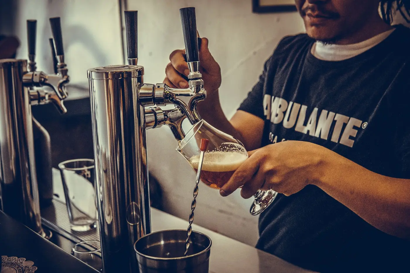 A glass being poured from a row of taps behind a bar