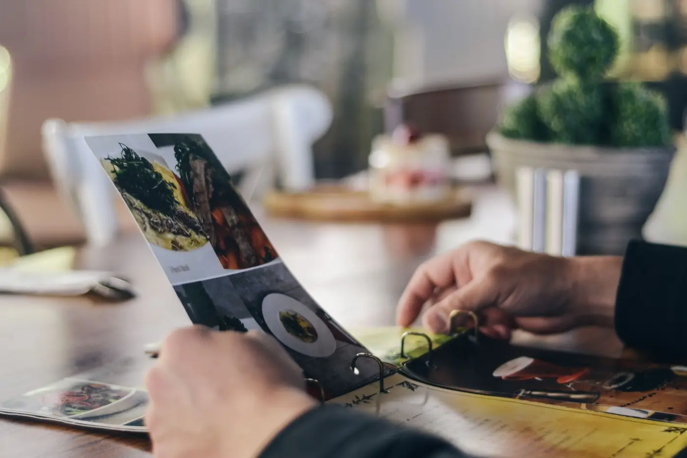 A guest turning the pages of a printed menu at a restaurant table