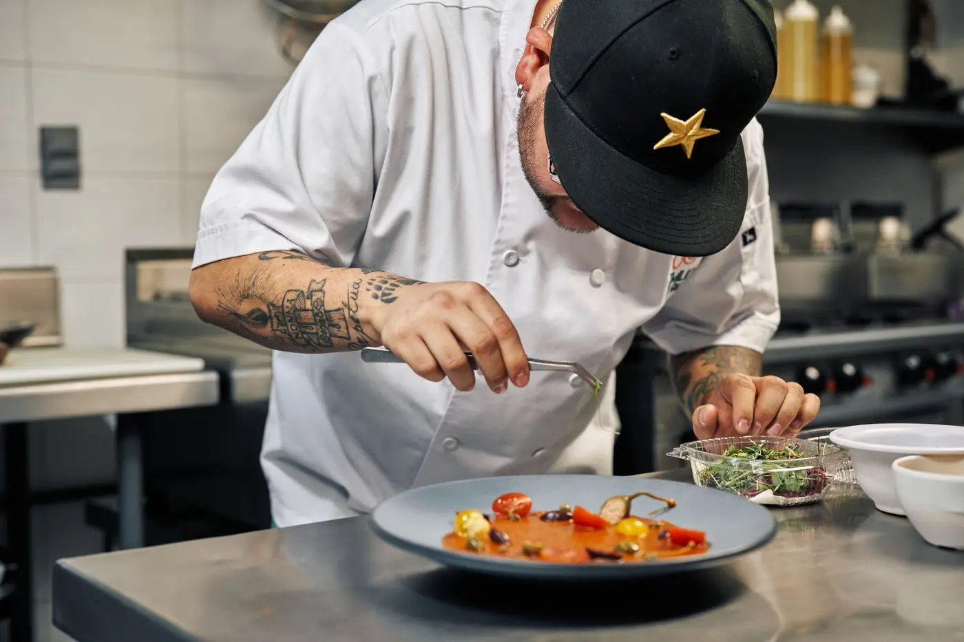 A chef finishing a plate on the pass in a restaurant kitchen